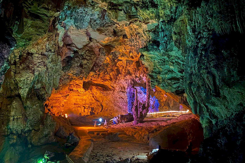 This extensive limestone cave features stunning stalactite and stalagmite formations illuminated by soft lighting